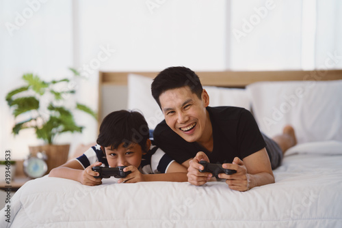 Tableau sur toile dad and son having goodtime playing vdo game together on bed at home