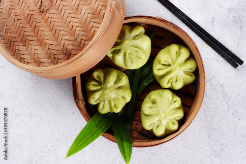 Bakpao or pao or chinese steamed bun in traditional bamboo steamer tint with pandan flavour in top view.