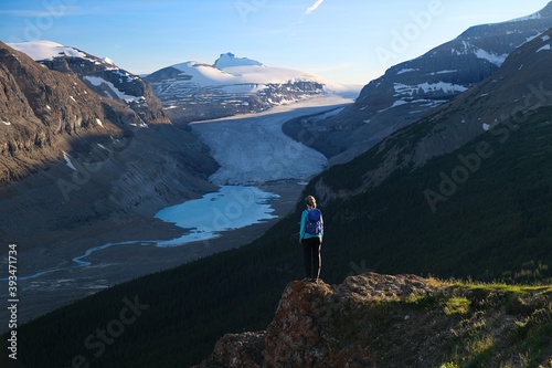 Woman hiker  backpacker  on steep cliff above glacial lake in Columbia Icefield. Jasper National Park. Alberta. Canada 