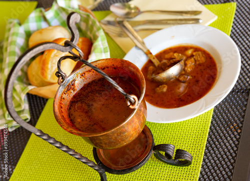 Small copper cauldron with appetizing spicy goulash Bograc traditionally cooked with potatoes. Authentic Slovenian cuisine photo