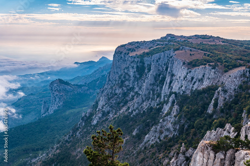 A majestic view of the rocky mountains and the valley in fog and clouds. Creamy fog covered the mountain valley in sunset light. Picturesque and gorgeous scene. Misty sunset over Crimea Mountains