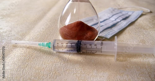 syringe with injection and face mask and hourglass