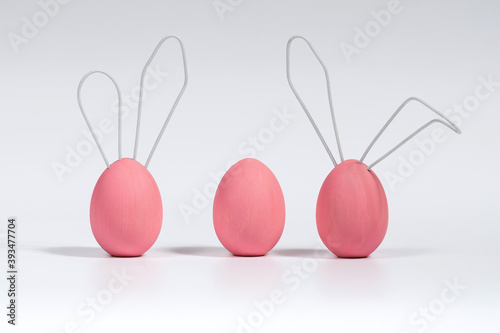 Three pink Easter eggs, cute bunnies. Concept decoration for a Happy Easter. White isolated background with soft shadow.
