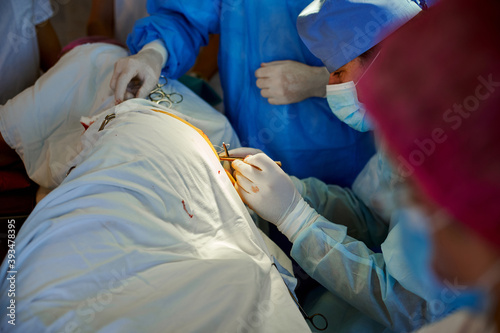 Surgery. Side view of a surgeon stitching a wound using a surgical instrument.