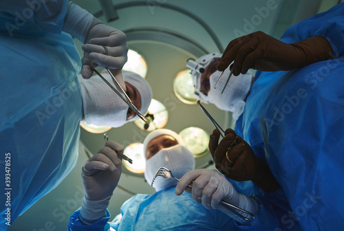 View through the eyes of a patient during a surgical operation. Three surgeons with various instruments in their hands.
