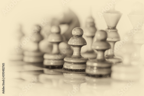 Wooden chess pieces stand on the board in the starting position before the battle.