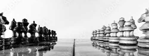 Wooden chess pieces stand on the board in the starting position before the battle. photo