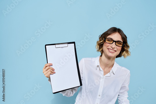 Business woman with documents in a folder on a blue background and in a light shirt glasses on her face