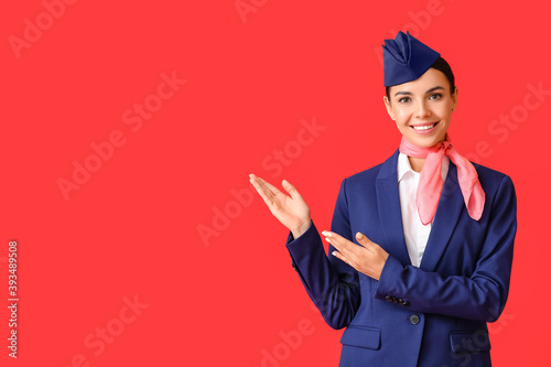 Beautiful stewardess showing something on color background photo