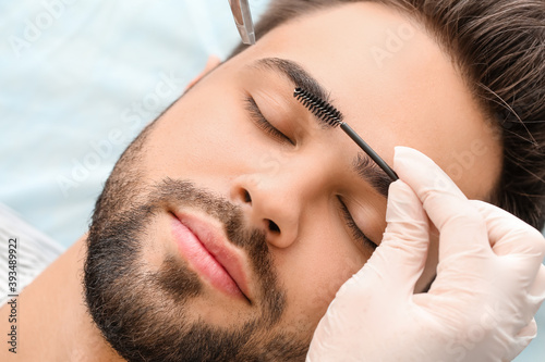 Obraz na plátně Young man undergoing eyebrow correction procedure in beauty salon