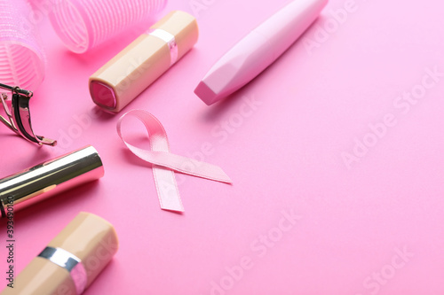 Pink ribbon and cosmetics on color background. Breast cancer awareness concept