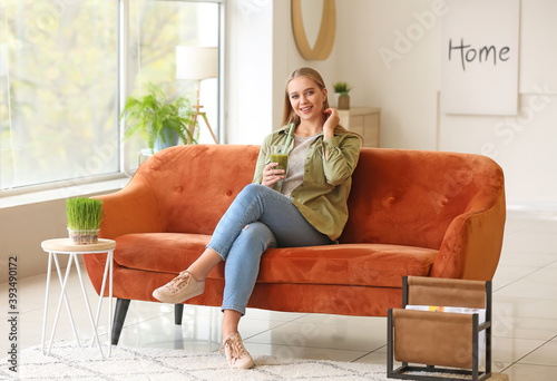 Cuadro en lienzo Young woman drinking wheatgrass juice at home