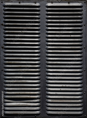 Rusty metal grilles, painted with paint and peeled off from old age, ventilation holes for air ingress in industrial facilities, an electric shield, an opening door