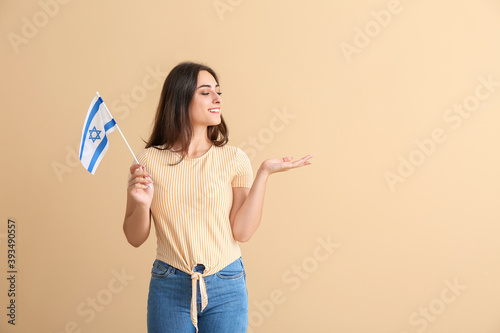 Young woman with the flag of Israel showing something on color background