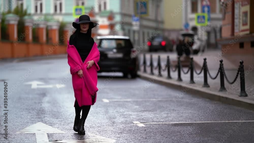 fashionista is walking on road in small town in autumn day, playing with her stylish pink coat fashionista is walking on road in small town in autumn day, playing with her stylish pink coat