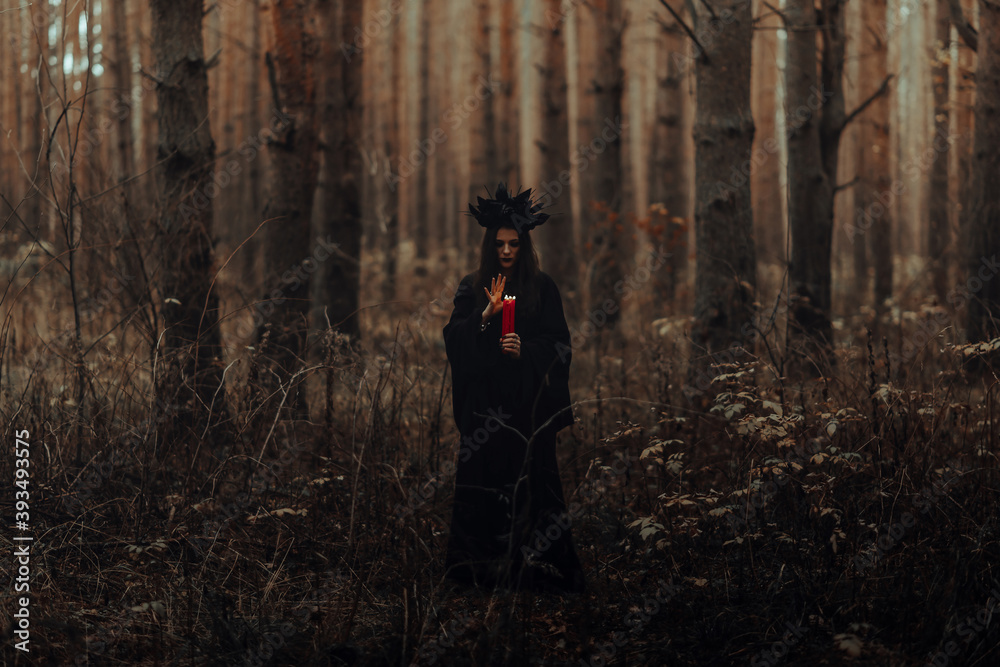 Obraz premium dark terrible witch with candles in her hands performs an occult mystical ritual