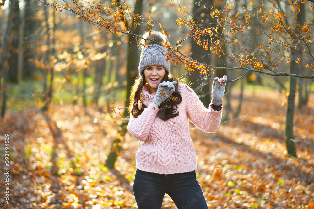 girl in a pink sweater and a knitted hat in the autumn forest portrait