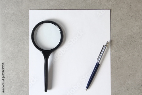 Template of white paper with a ballpoint pen, magnifying glass on light grey concrete background. Concept of new idea, business plan and strategy, empty space for text