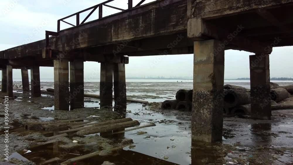 Fly low under concrete pier to fisherman digging for bait low tide Fly low under concrete pier to fisherman digging for bait low tide