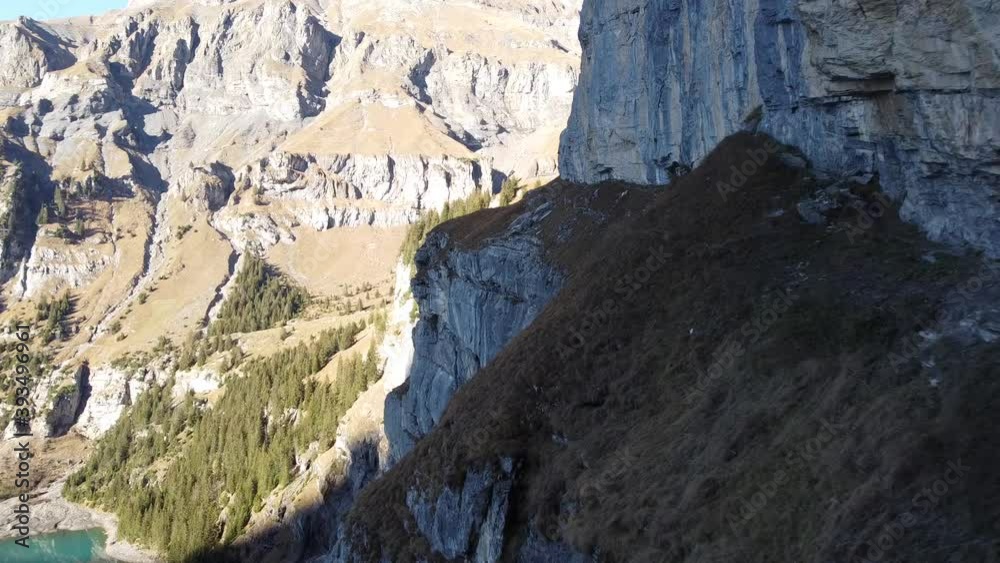 Drone flight along a dangerously steep mountain hiking path in the lush green Swiss mountains above the beautiful Oeschinensee, perfect sunny weather Drone flight along a dangerously steep mountain hiking path in the lush green Swiss mountains above the beautiful Oeschinensee, perfect sunny weather