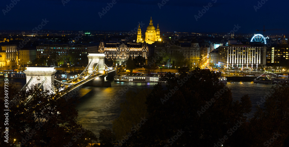 Illuminated Szechenyi Chain Bridge over Danube on background with St.Stephen Basilica, Budapest
