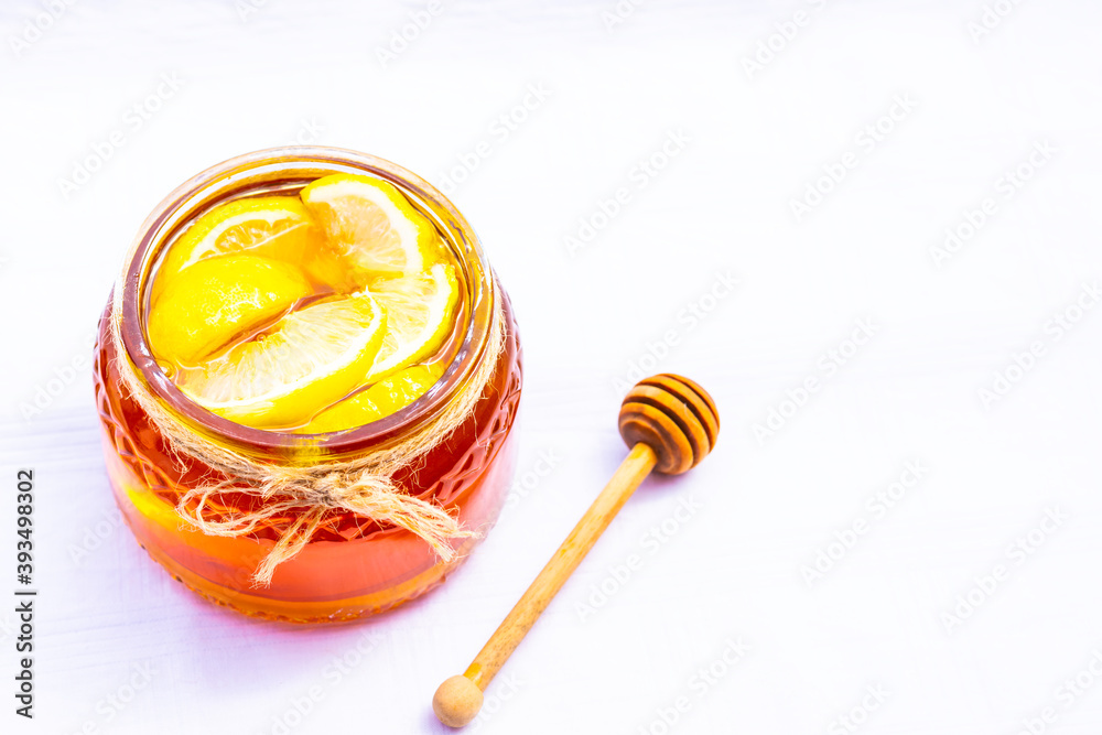Honey in a glass jar with lemon on white background Honey in a glass jar with lemon on white background