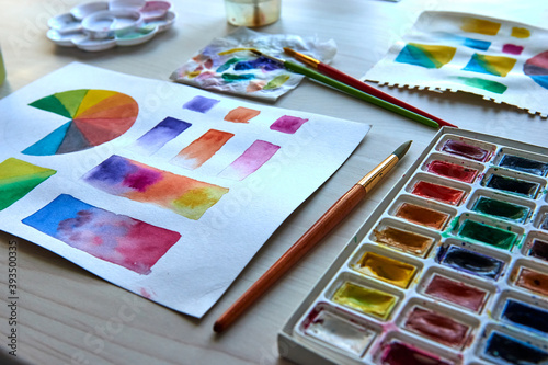 Artist's workplace. Art supplies brushes, paints, watercolors. Art studio. Drawing lessons. Creative workshop. Design place. Watercolor color wheel and palette. Color theory beginner hobby lessons.