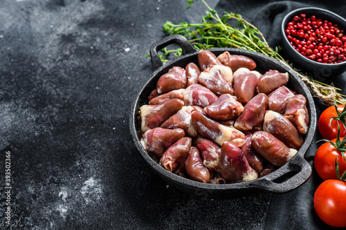 Raw chicken hearts in a pan. Organic offal. Black background. Top view. Copy space