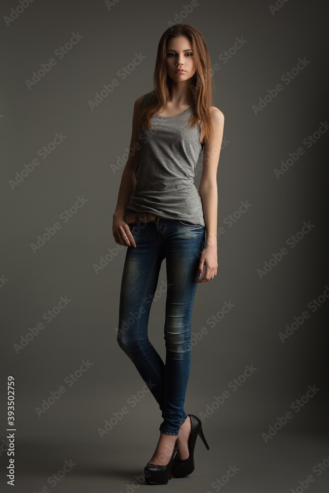 beautiful slender model in a gray t-shirt and jeans on a gray background beautiful slender model in a gray t-shirt and jeans on a gray background