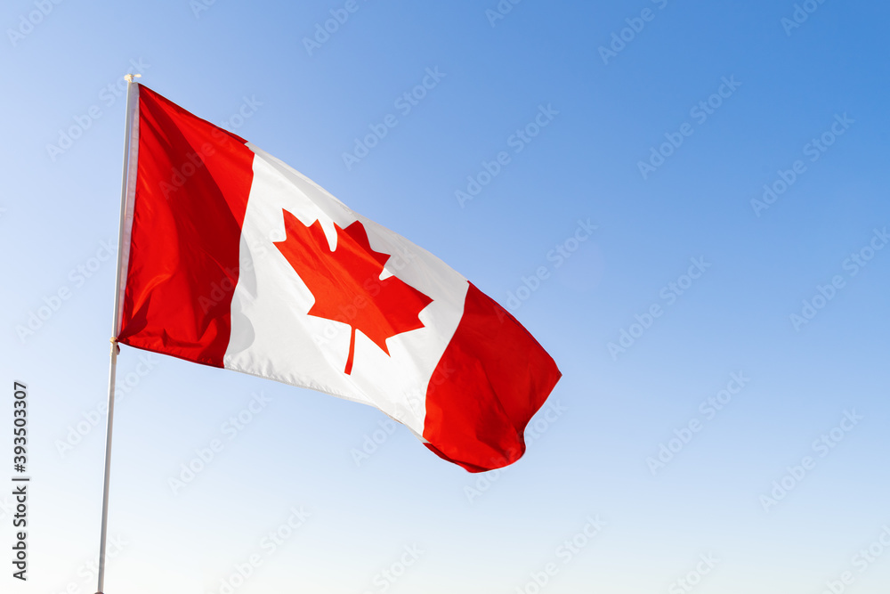 Flag of Canada waving against blue sky Flag of Canada waving against blue sky