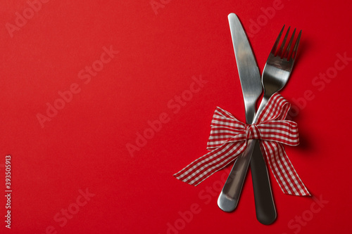 Cutlery with checkered bow on red background