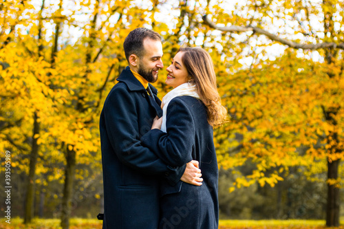 Couple in coats hugs outside in the fall
