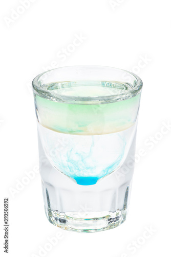 Alcohol shots cocktail in a glass isolated on white background. Layered composed of green, white and blue liqueur