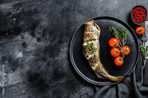Delicious grilled pollock with fresh thyme and tomatoes. Black background. Top view. Copy space