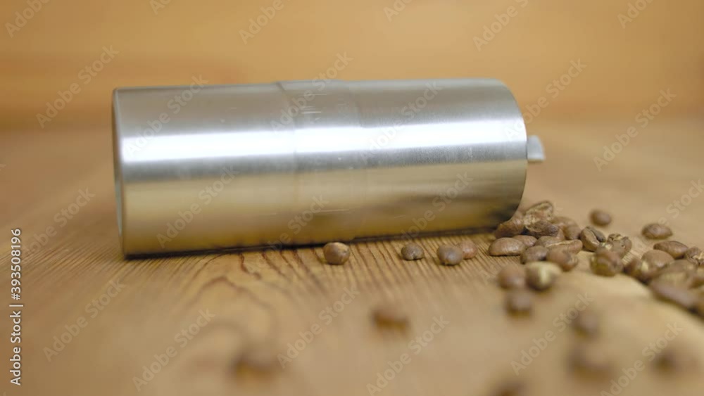 4K SLOW MOTION | Hand grinder full of coffee beans falling on the wooden kitchen desk in slow motion