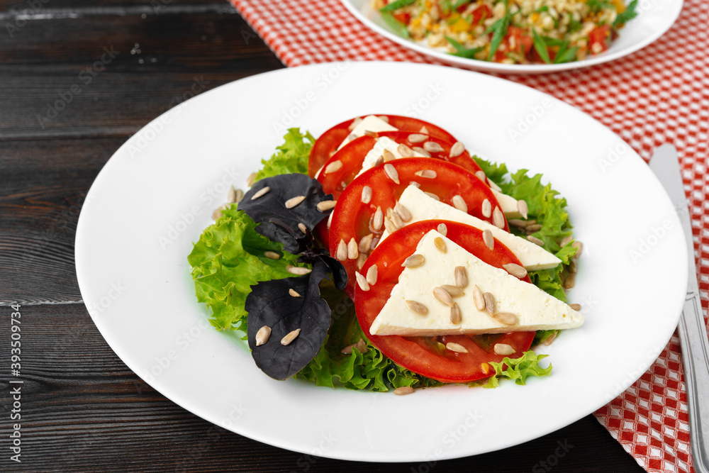 Salad with fresh tomatoes and brined cheese, sunflower seeds on top Salad with fresh tomatoes and brined cheese, sunflower seeds on top