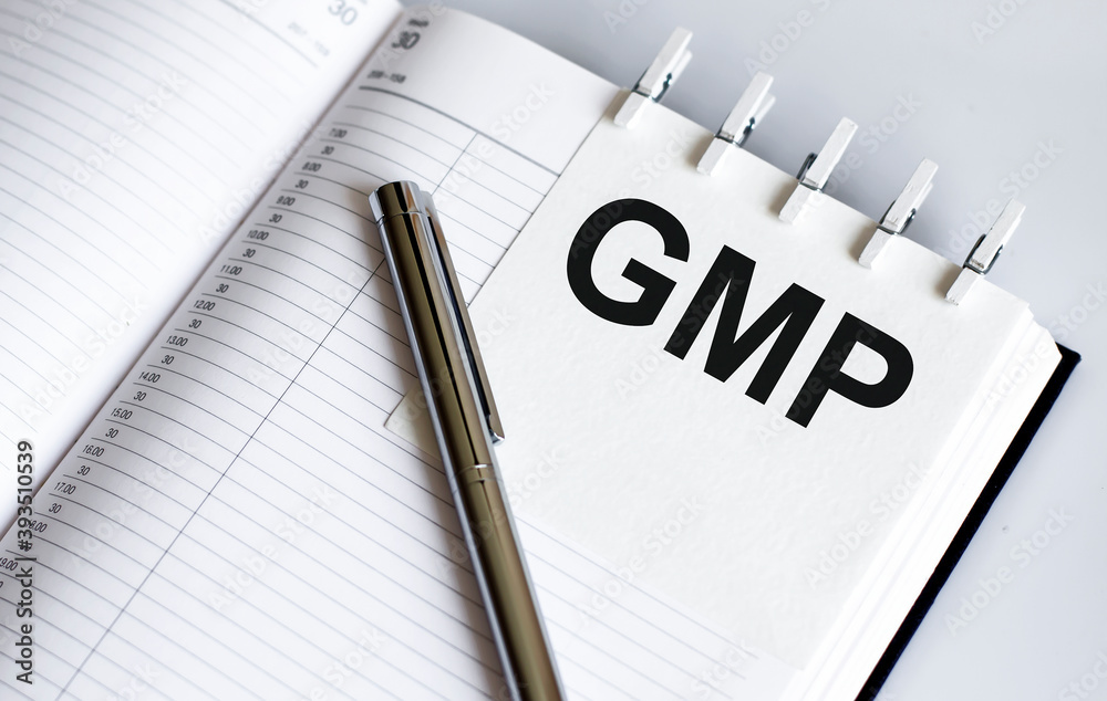 text GMP on the short note texture background with pen text GMP on the short note texture background with pen
