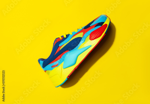 Multicolor sport shoes on yellow background with shadows. flatlay