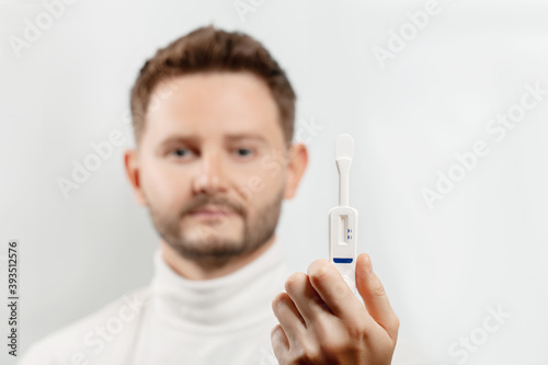 Man holding oral HIV test on face background.