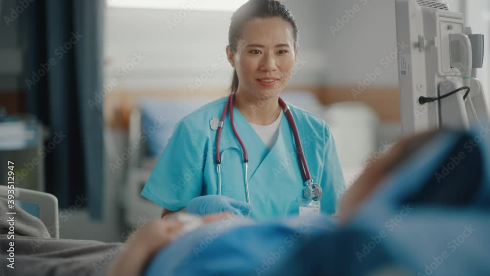 Hospital Ward: Portrait of Professional Chinese Head Nurse Doing Patient Vital's Checkup, Monitoring Equipment, Medicine Delivery. Nurse Talks to Person Getting Well after Successful Surgery