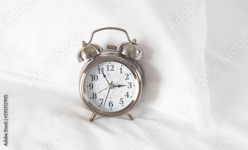 Classic alarm clock on bed.