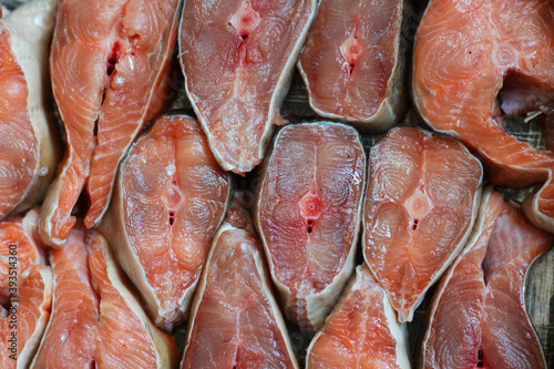 Sliced pieces of red fish are arranged in a row. Abstract background of chum salmon or pink salmon close-up.