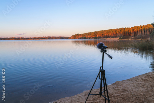 Portable recorder stands on a tripod on the lake shore. Recording sounds of nature
