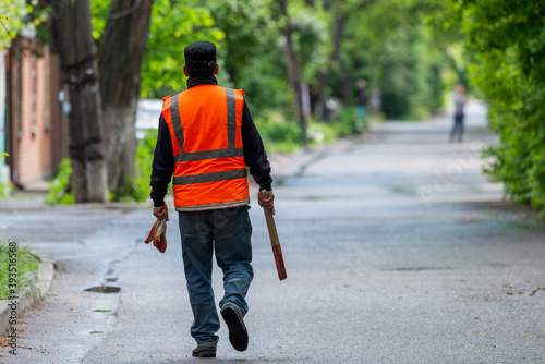 A janitor with hand equipment is walking down the street. Work of housing and communal services © rostovdriver