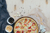 flat pizza, top photo, ingredients and kitchen utensils laid out around. Wooden background and towel