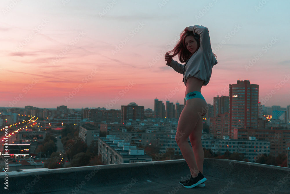 girl in hoodie and panties posing on the rooftop during sunset