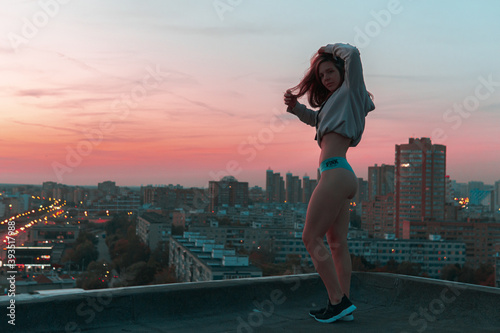 girl in hoodie and panties posing on the rooftop during sunset