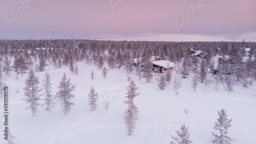 Visit Lapland Holidays. Aerial drone panorama shot of the forest covered in snow winter and the village inside the Arctic Circle. Lapland, Finland. Winter sunrise. Igloos and cabins covered with snow © oluuuka
