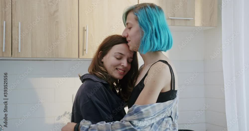 Portrait look at camera in the morning tender hugs of two girls in love with non traditional sexual orientation LGBT lesbians in the kitchen in a cozy home environment