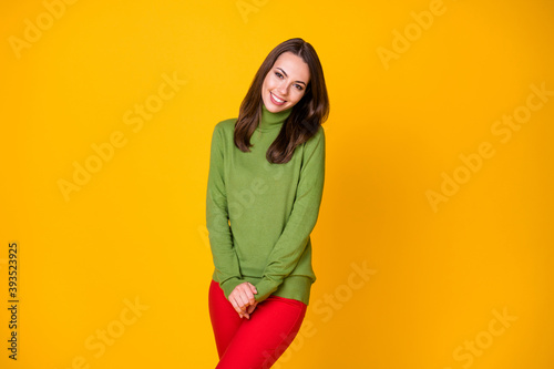 Portrait of attractive shy cheery girl wearing cosy clothing posing isolated over bright yellow color background © deagreez